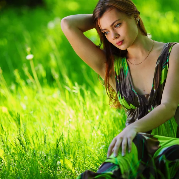 Brünette sitzt auf grünem Gras — Stockfoto