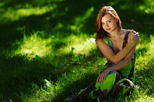 Брюнетка сидит на зеленой траве — стоковое фото