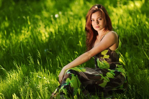 Брюнетка сидить на зеленій траві — стокове фото