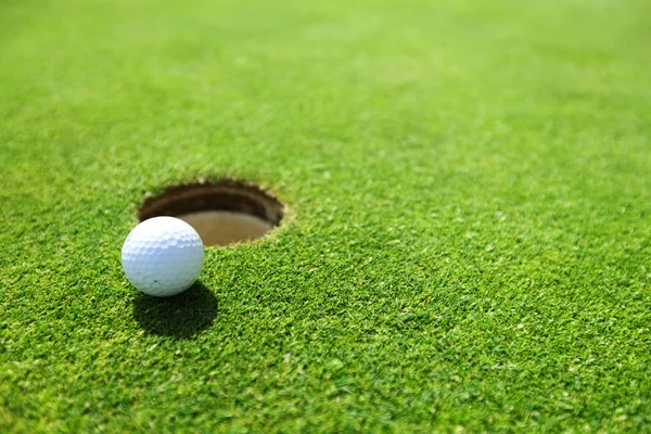 Golf ball on lip of cup — Stock Photo, Image