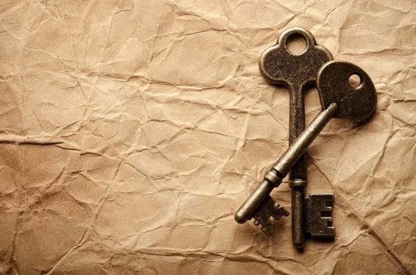 Ключи на старом бумажном фоне — стоковое фото