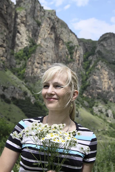 Retrato de mulher feliz com camomilas em umas montanhas de fundo — Fotografia de Stock
