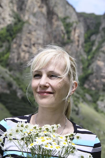 Portrait of happy woman with camomiles on a background mountains — Stock Photo, Image