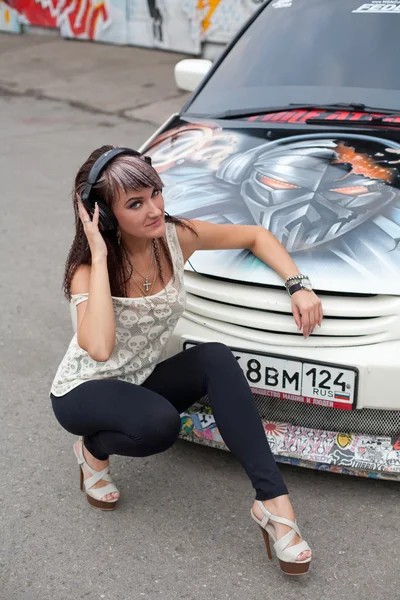 Girl in headphones sitting near the car — Stock Photo, Image