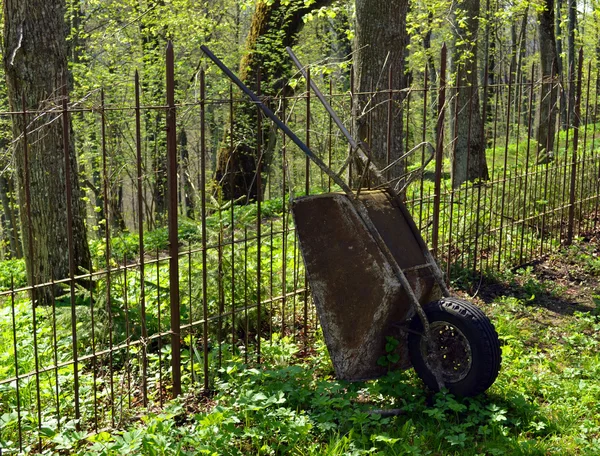 Old rusty garden tool wheelbarrow metal fence — Stock Photo, Image
