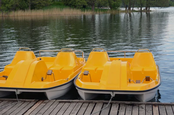 Желтые водные велосипеды, запертые на озерном пирсе — стоковое фото