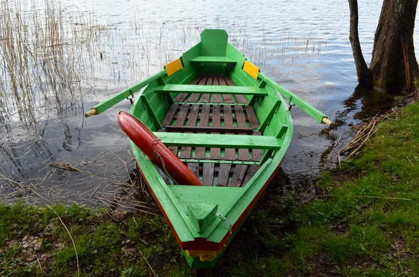 เรือพายเรือไม้บนชายฝั่งทะเลสาบและวงกลม — ภาพถ่ายสต็อก