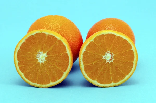 Pomarańczowy owoc pełny i przekroju na niebieskim tle — Zdjęcie stockowe