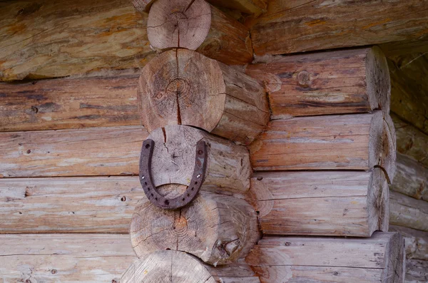La herradura cuelga en la esquina de la casa de madera. Luch símbolo — Foto de Stock