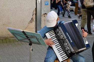 Child plays ancient accordion. Street music day clipart