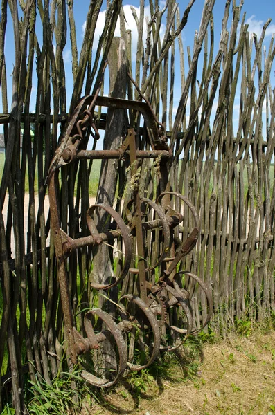 Old corroded field harrow tool stand wooden fence — Stock Photo, Image