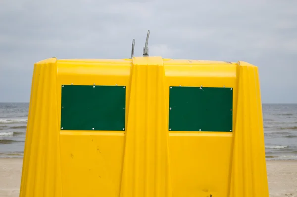 Крупный план контейнера с желтыми отходами на морском пляже — стоковое фото