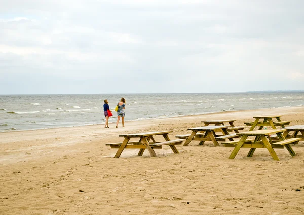 Wooden benches table sea coast teenage girls walk — Stock Photo, Image