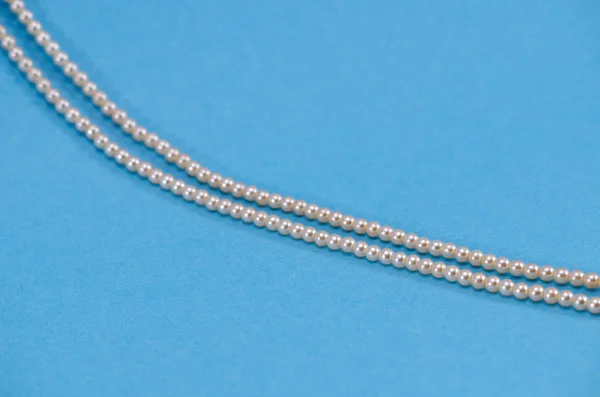 Pearl necklace fragment closeup on blue background — Stock Photo, Image