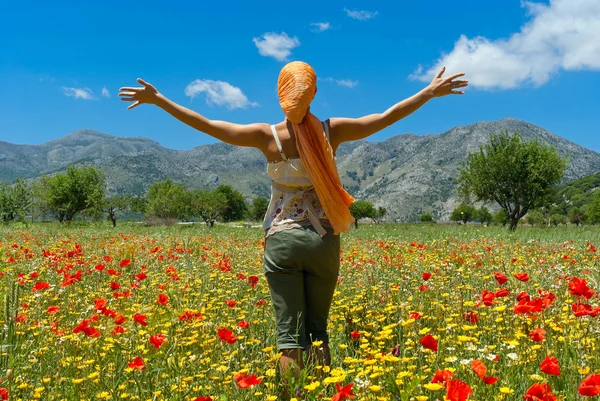 Szczęśliwa młoda kobieta stojąc w kolorowy kwiat pole lasithi p — Zdjęcie stockowe