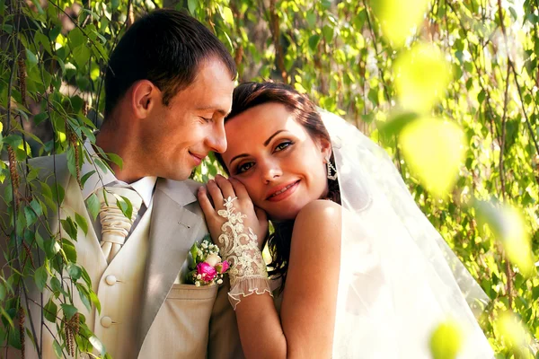 Bruden och brudgummen poserar i park — Stockfoto