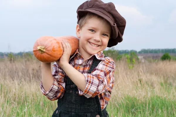 Smiling boy with pumpkin on his shoulder — Stockfoto