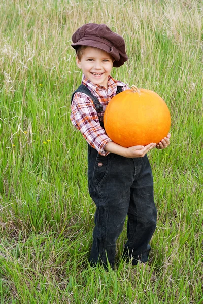 Smiling boy standing with pumpkin — Stock Photo, Image