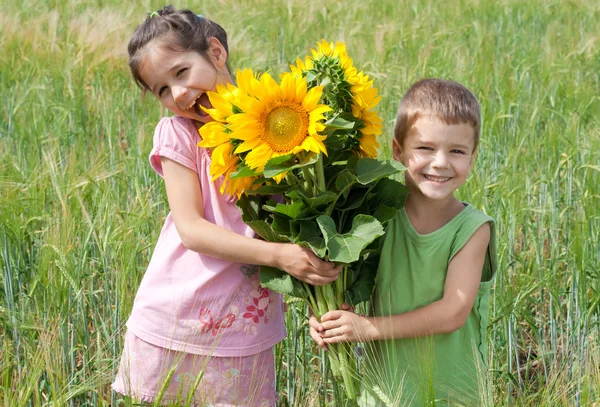 Dwoje dzieci z słoneczniki w polu pszenicy — Zdjęcie stockowe