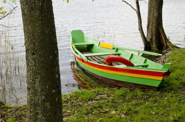 Барвистий човен на літньому узбережжі озера — стокове фото