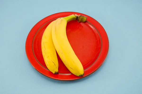 Duas bananas amarelas em placa vermelha — Fotografia de Stock