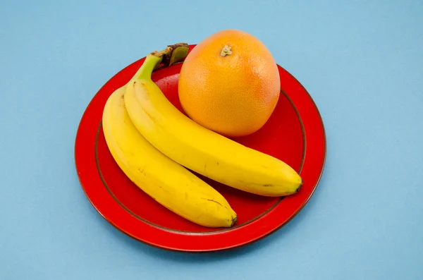 Μπανάνα και γκρέιπφρουτ σε ερυθρή πλάκα — Φωτογραφία Αρχείου