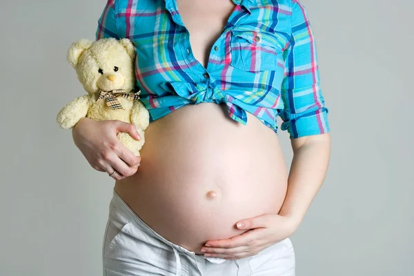 Donna incinta accarezzando il ventre con un orso in mano e c — Foto Stock