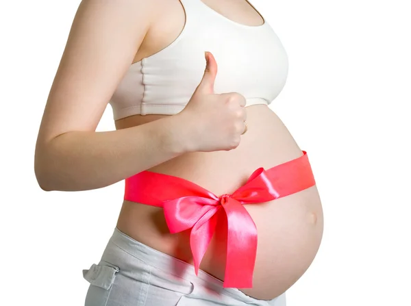 Όμορφη νεαρή έγκυο γυναίκα με ροζ κορδέλα. δείχνει τον αντίχειρα — Φωτογραφία Αρχείου