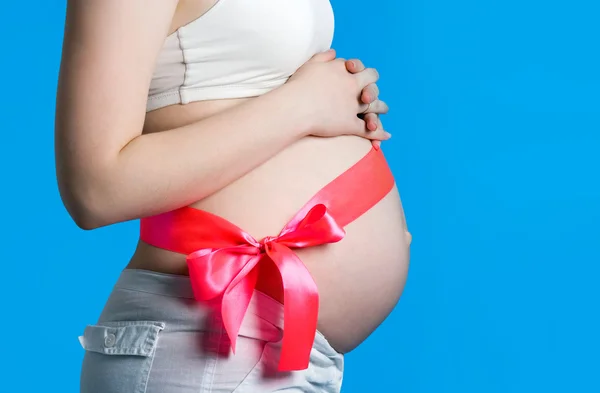 Mooie jonge zwangere vrouw met een roze lint. toont de duim — Stockfoto