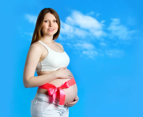 Beautiful pregnant woman in the blue sky background — Stock Photo, Image