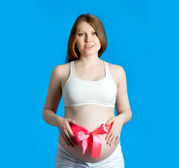 Mavi bir arka plan üzerinde güzel bir hamile kadın — Stok fotoğraf