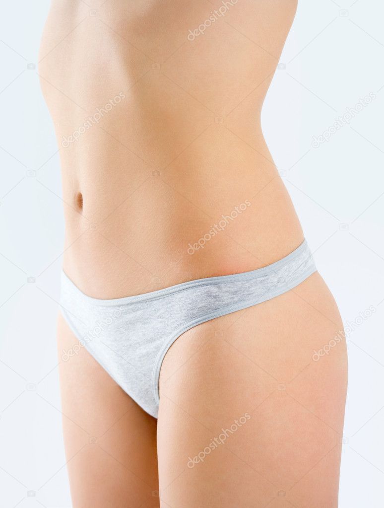 Slim tanned woman's body isolated over gray background. Healthy