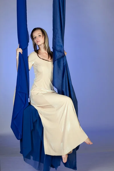 Una ragazza con un vestito lungo seduta su un'altalena — Foto Stock