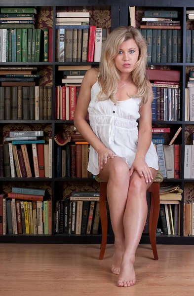 Vrouw op zoek naar een boek in de bibliotheek — Stockfoto