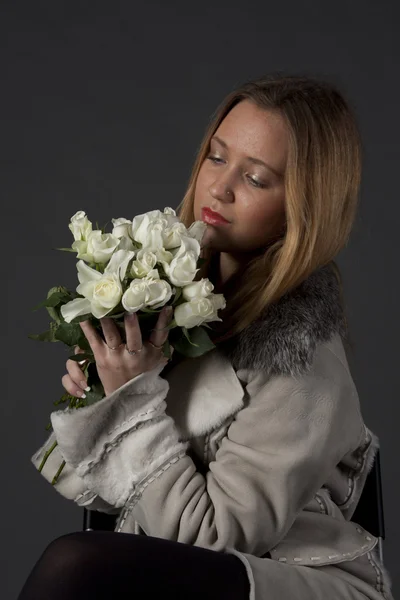 Portret van een mooi meisje in winterkleren met een boeket van bloemen — Stockfoto