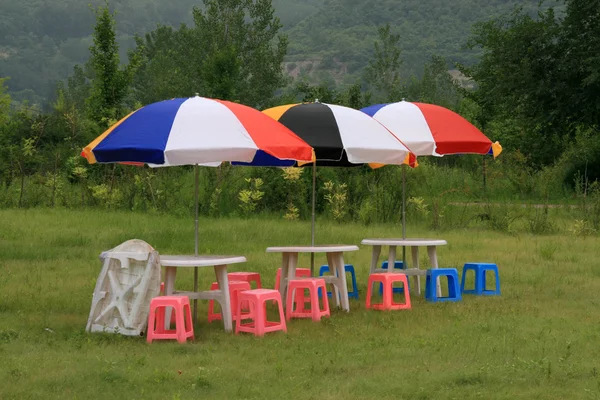 Kursi berwarna dan payung di rumput hijau — Stok Foto