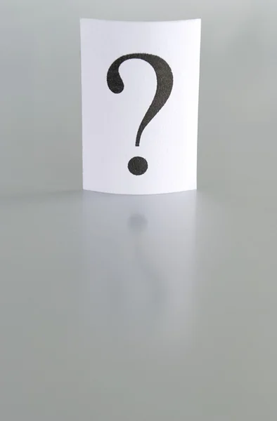 Großes Fragezeichen auf einem Blatt Papier auf grauem Hintergrund — Stockfoto