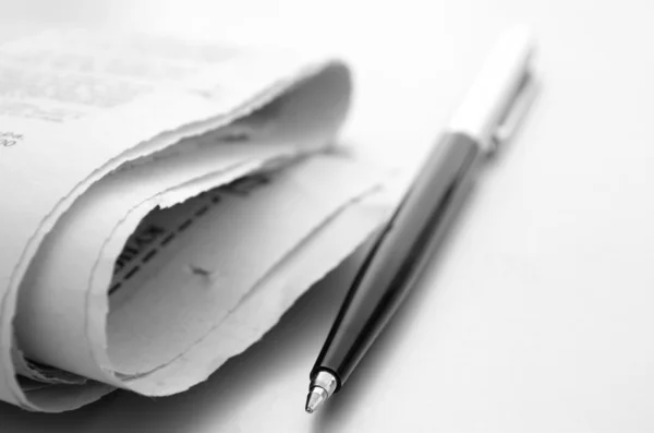 O jornal e a caneta de bola em uma mesa — Fotografia de Stock