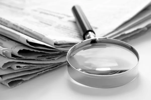 Newspaper and a magnifying glass — Stock Photo, Image