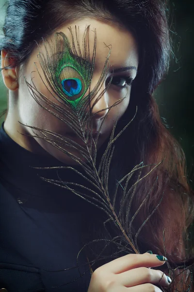 Beauty with a peacock feather — Stock Photo, Image