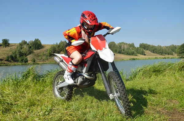 The girl sitting on a sport bike, amid lakes and forests. — Stockfoto
