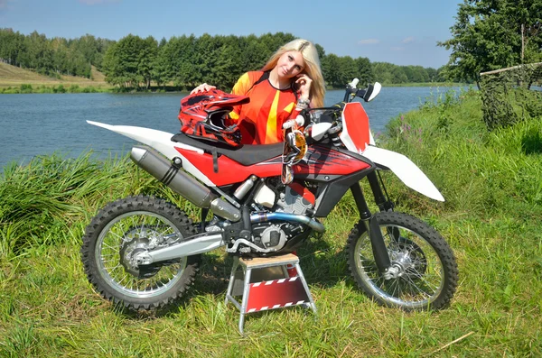 Ragazza è in piedi appoggiato sulla moto per motocross — Foto Stock