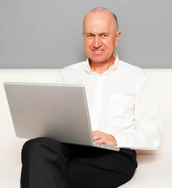 Homem sênior com laptop online — Fotografia de Stock