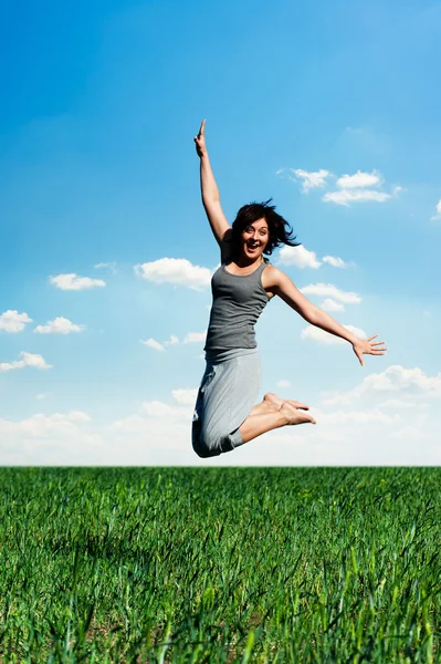 Młoda kobieta, skoki na polu w słoneczny dzień — Zdjęcie stockowe