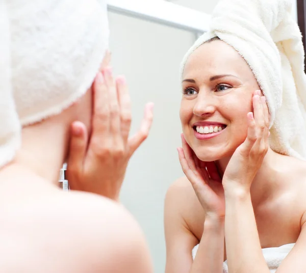 Mujer sonriente en toalla mirando en el espejo — Foto de Stock