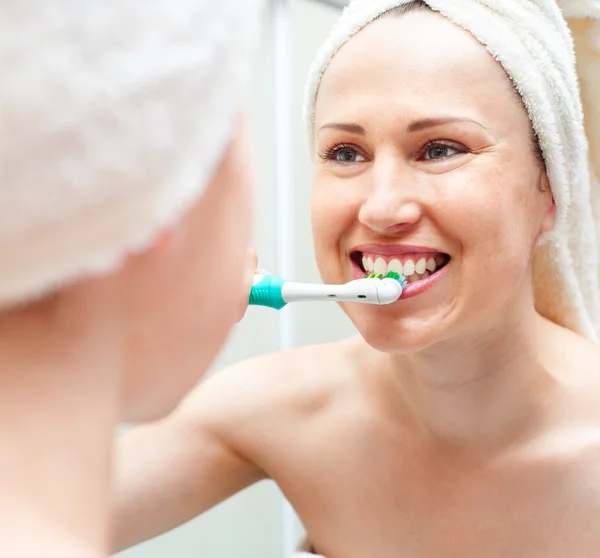Mulher limpeza de dentes perto do espelho — Fotografia de Stock