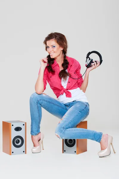 Studio shot of smiley woman sitting on speakers — Stock Photo, Image