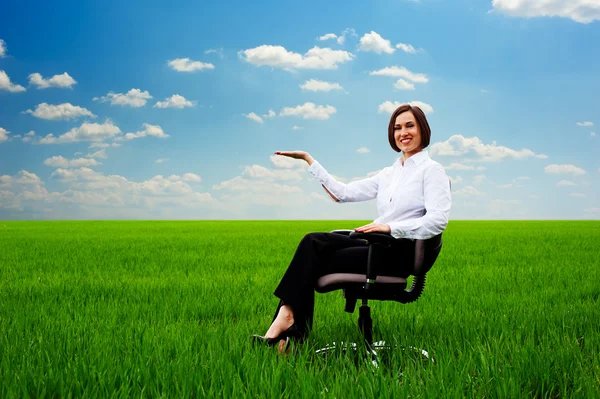 Mujer sentada en el sillón en el campo y sosteniendo algo — Foto de Stock