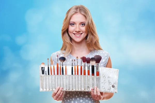 Frau mit Pinseln für Make-up über blauem Hintergrund — Stockfoto