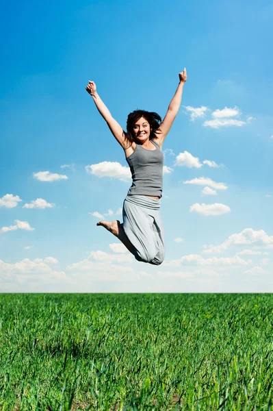 Vrouw springen op het veld op zonnige dag — Stockfoto